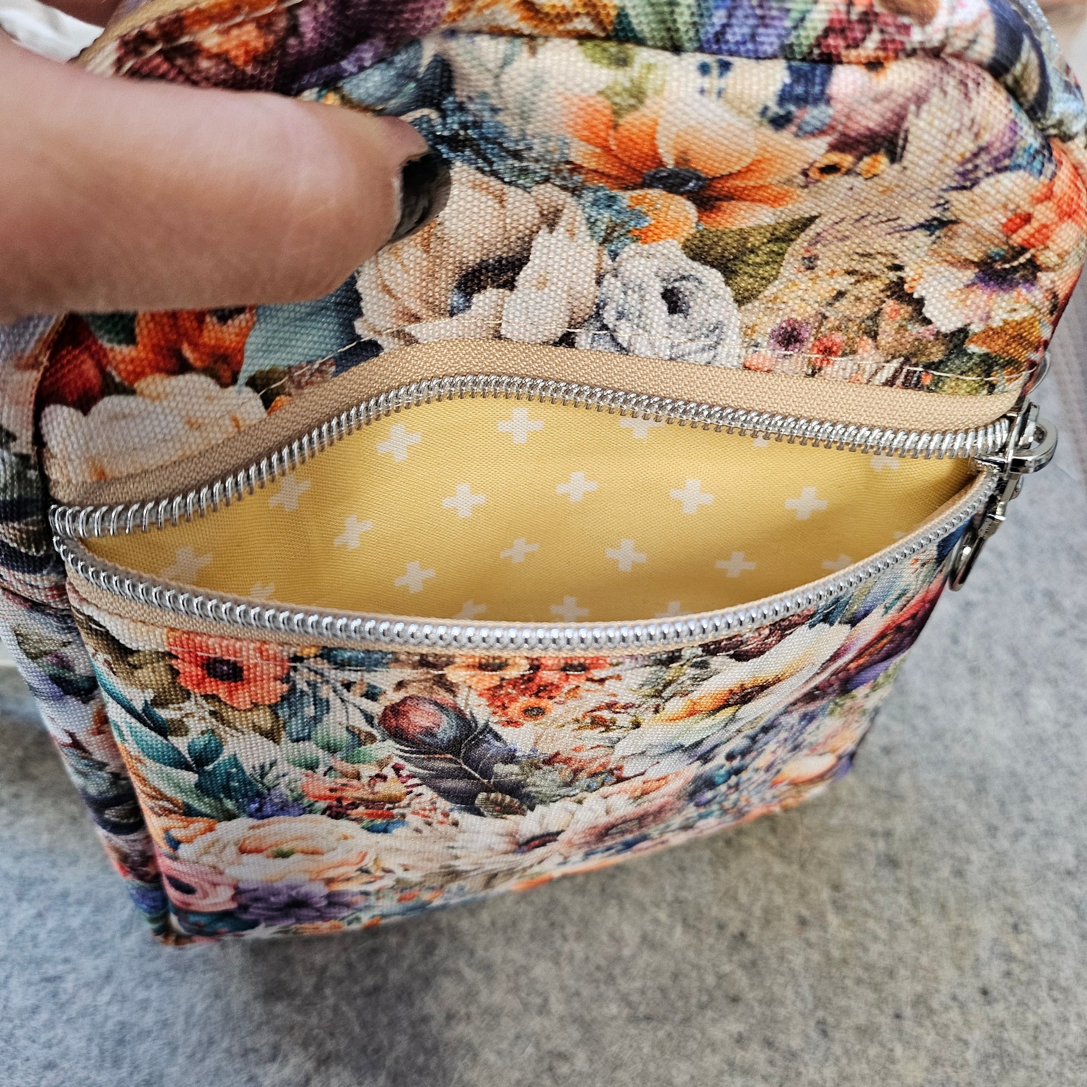 Floral-patterned cosmetic bag with a yellow interior on a gray background