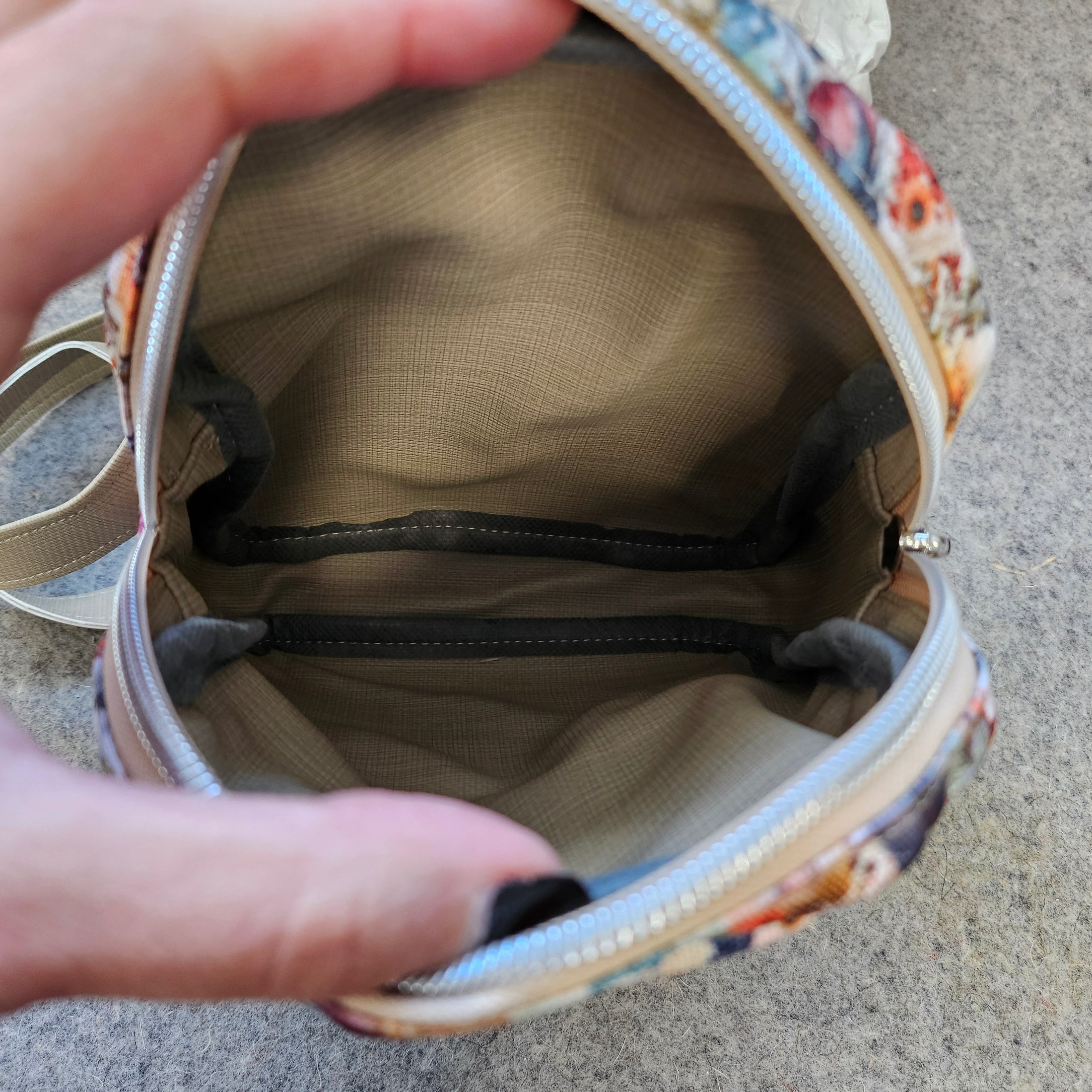 Floral-patterned makeup bag with a zipper, held open by hands on a neutral background