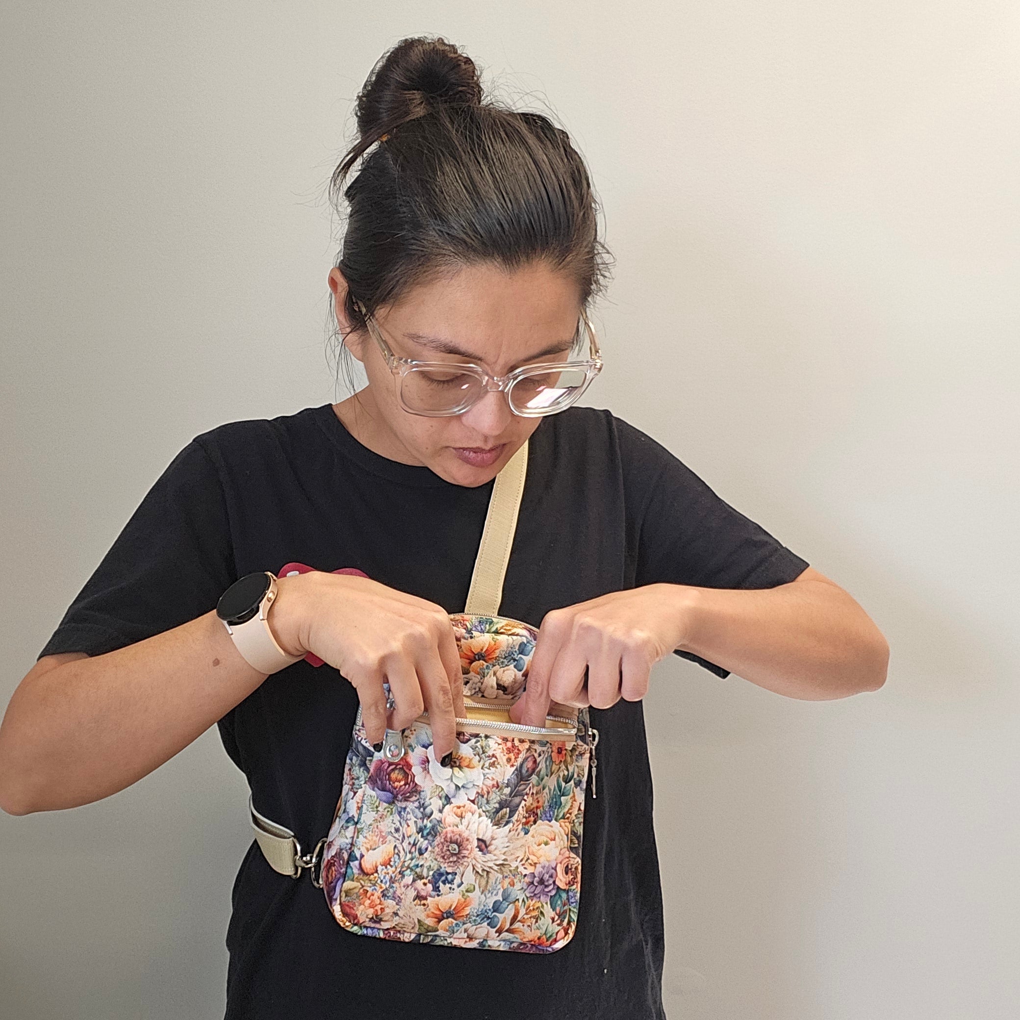 Person holding a floral clutch against a plain background