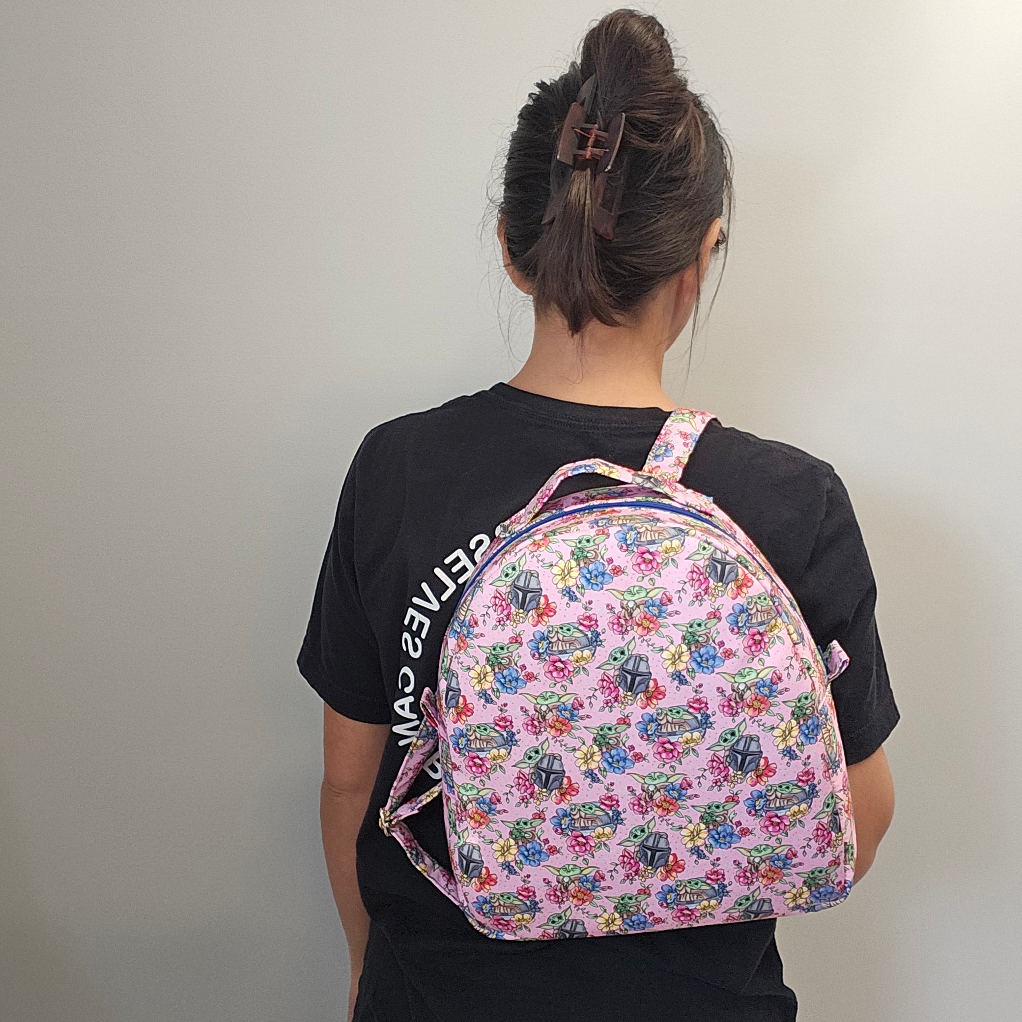 A person wearing the mandalorian backpack on one shoulder.