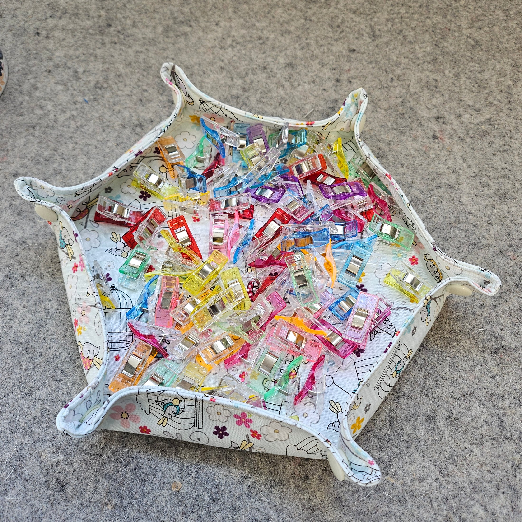 Crafting tray with sewing clips laying on a wool surface.