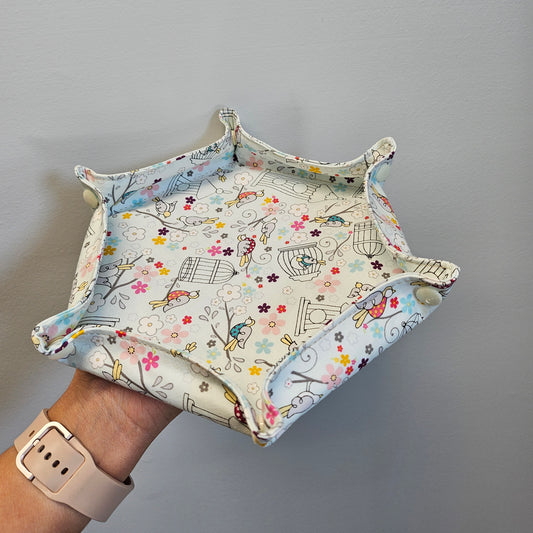 Hand holding a hexagon fabric tray in front of a gray wall.