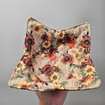 Load image into Gallery viewer, Floral patterned fabric held by a hand against a gray background
