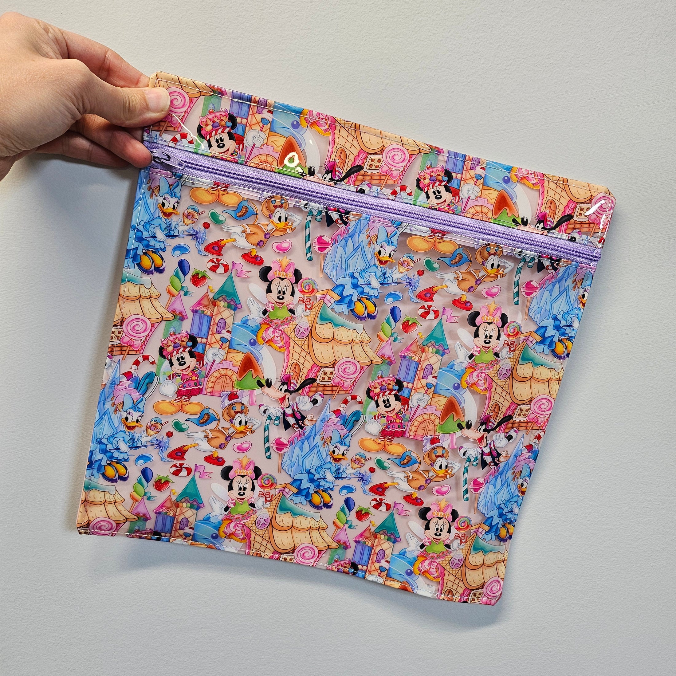 Colorful notebook with cartoon characters held by a hand on a light gray background