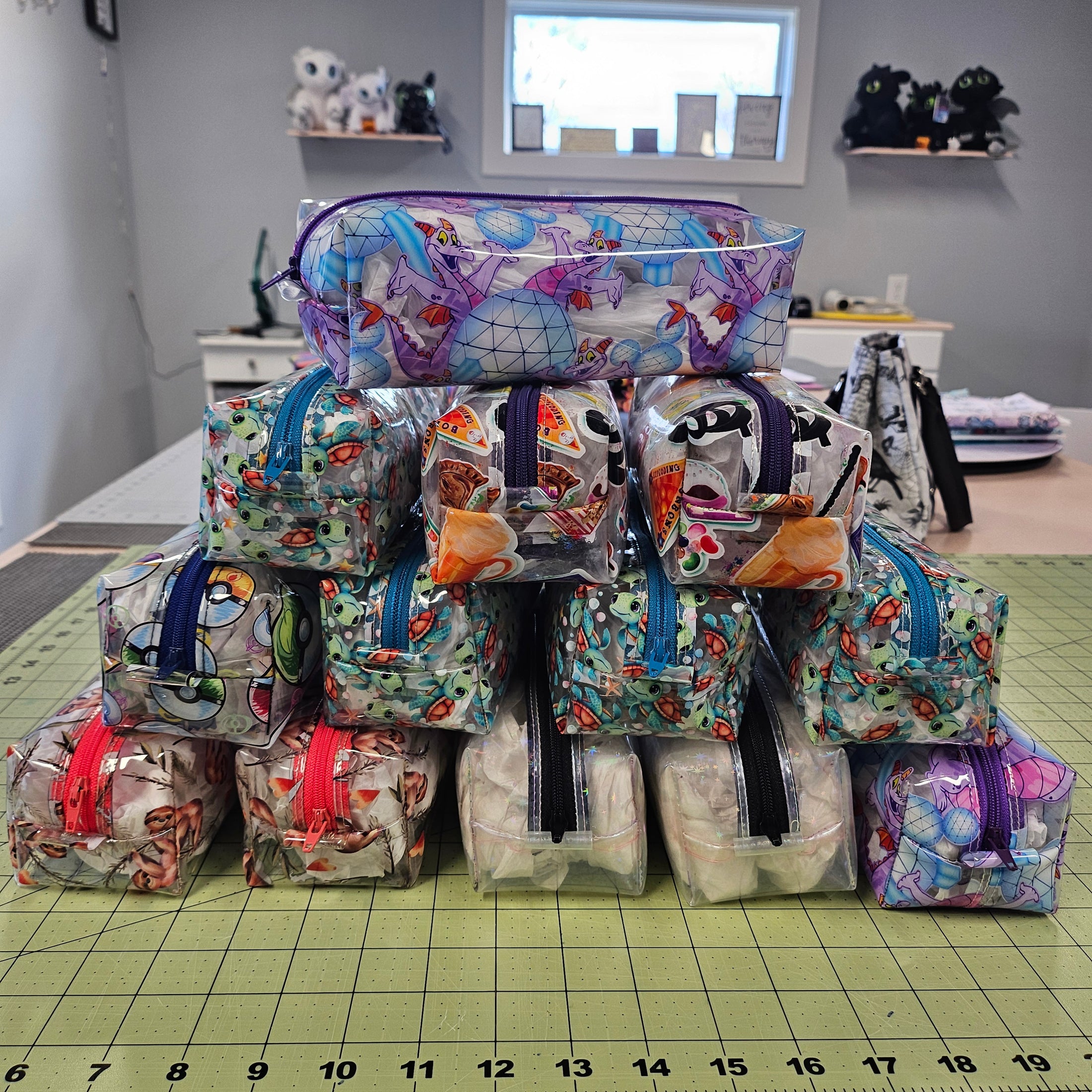 Stack of colorful fabric pouches on a green cutting mat with a ruler.