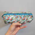Load image into Gallery viewer, Pencil case with turtle pattern held by a hand against a gray background
