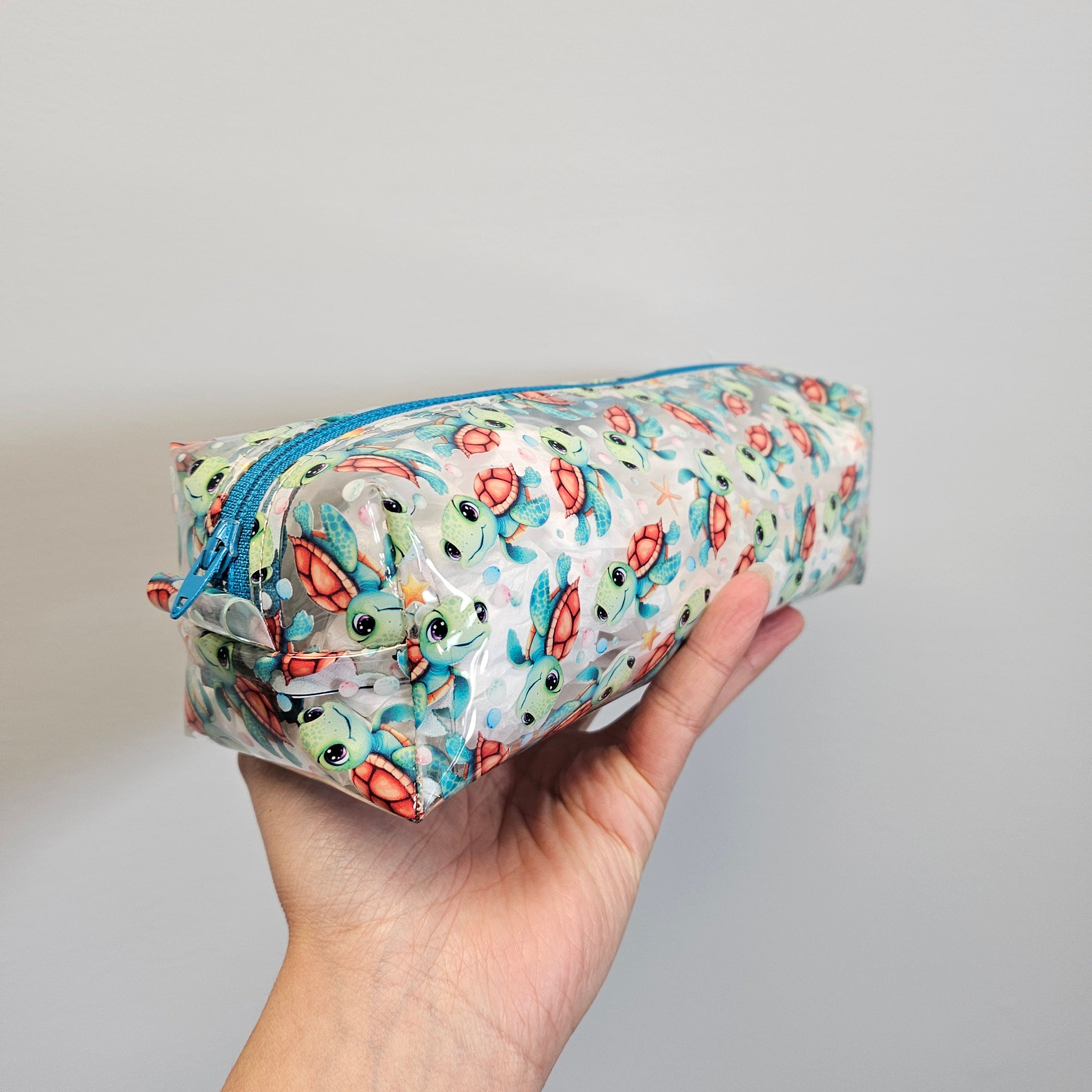 Hand holding a colorful rolled-up mat with a pattern of cartoon characters on a plain background