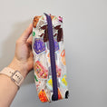 Load image into Gallery viewer, Hand holding a colorful pencil case with a purple zipper against a gray background
