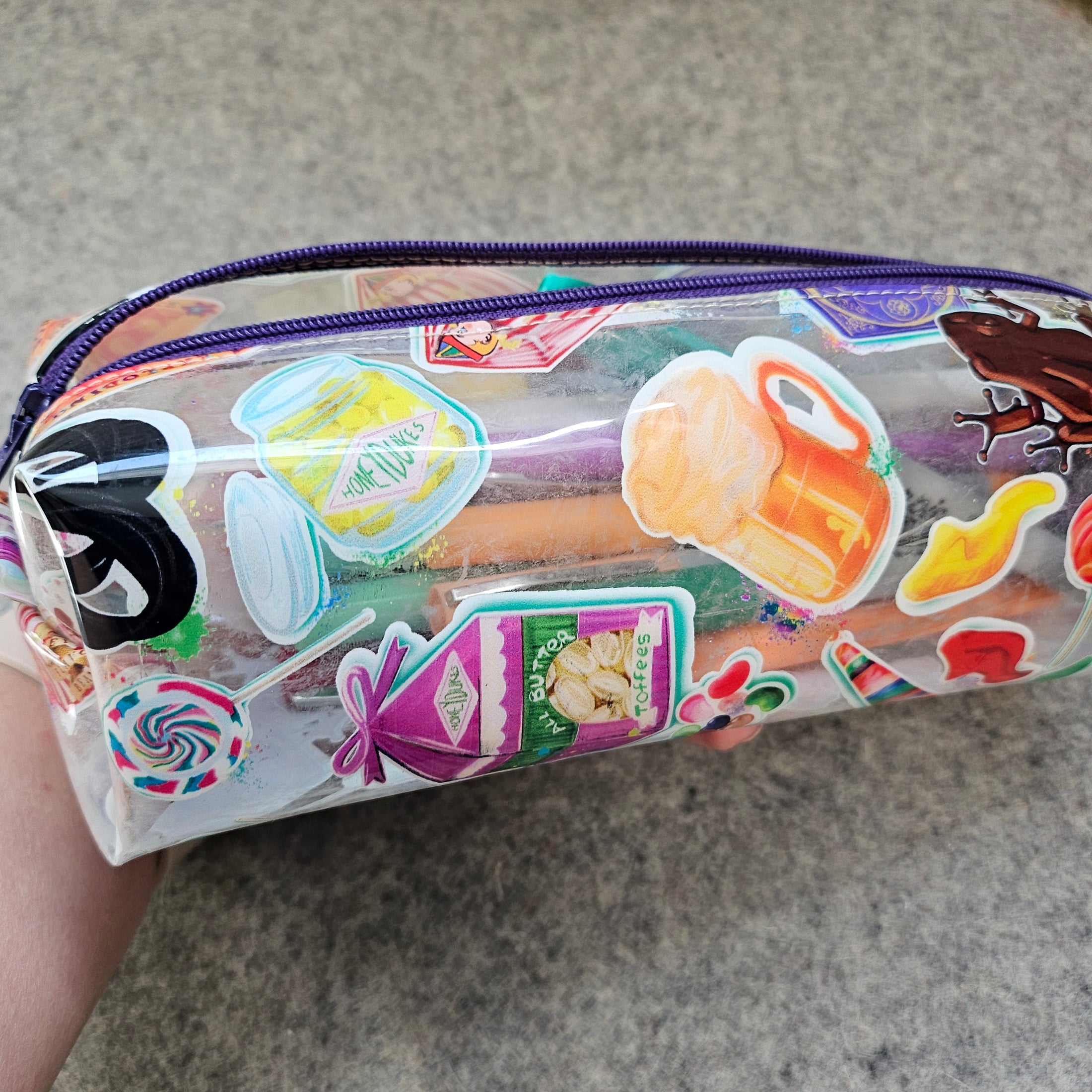 Clear pencil case with colorful stickers on a gray surface