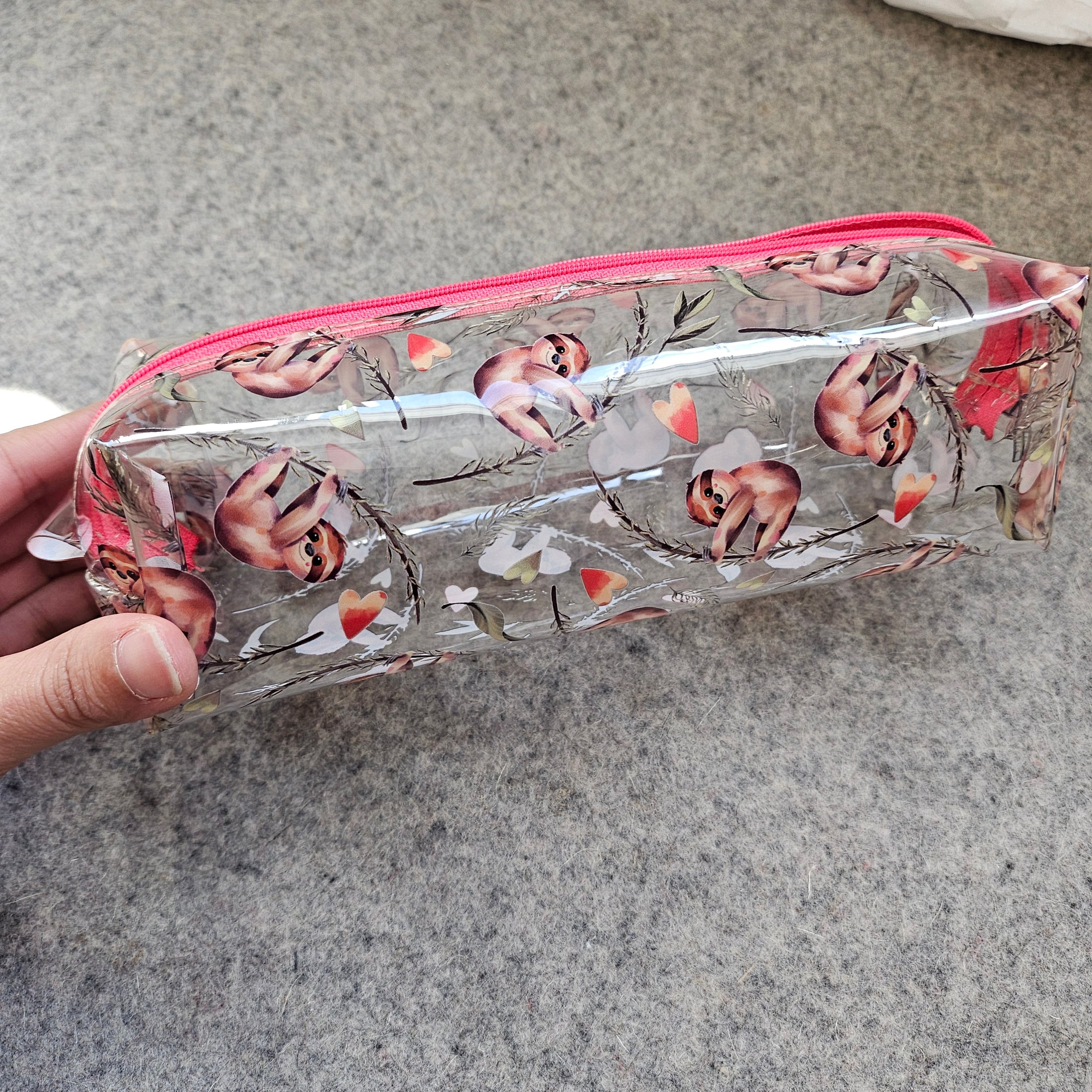 Clear pouch with nature-themed design held against a gray background