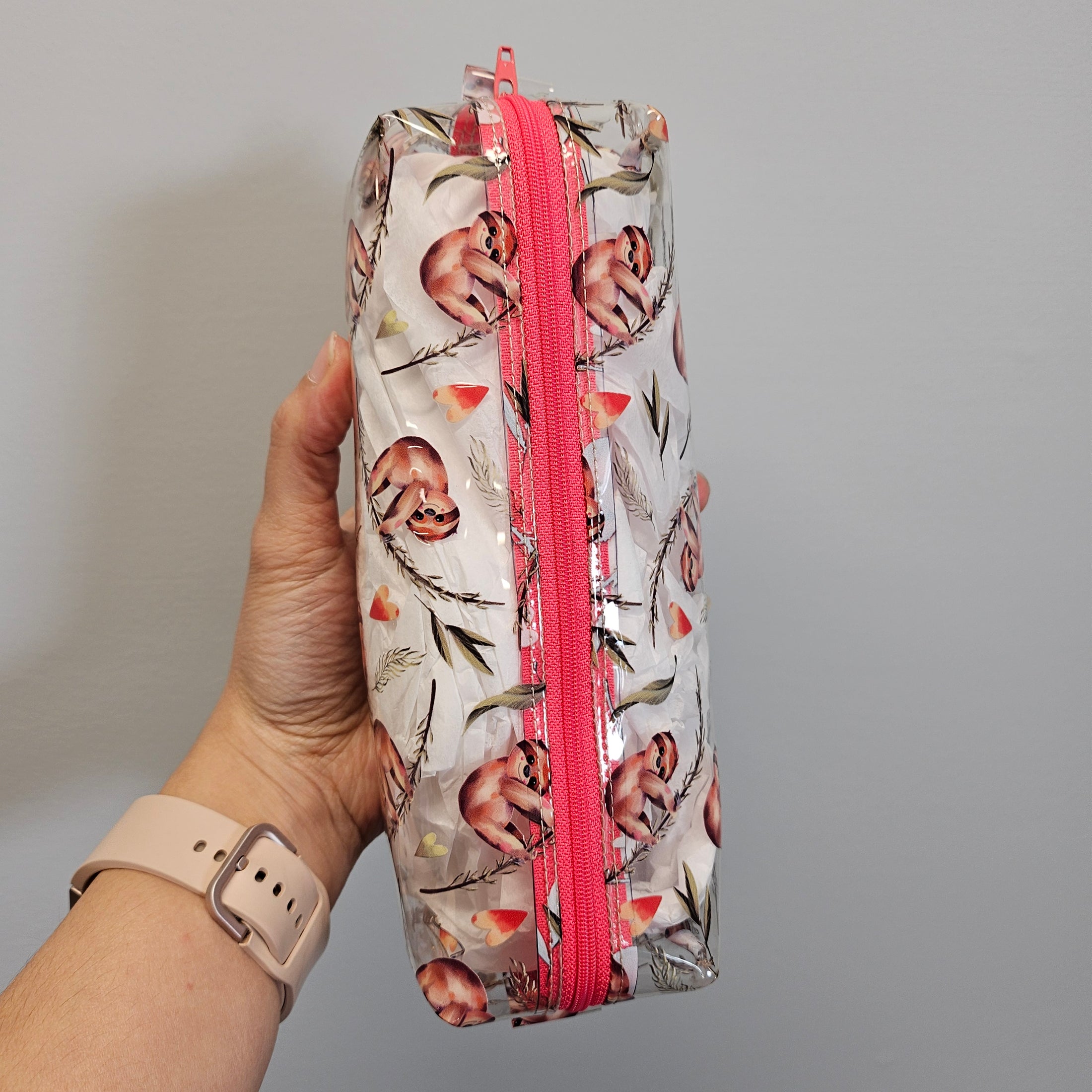 Floral-patterned pencil case with pink zipper held by a hand against a gray background