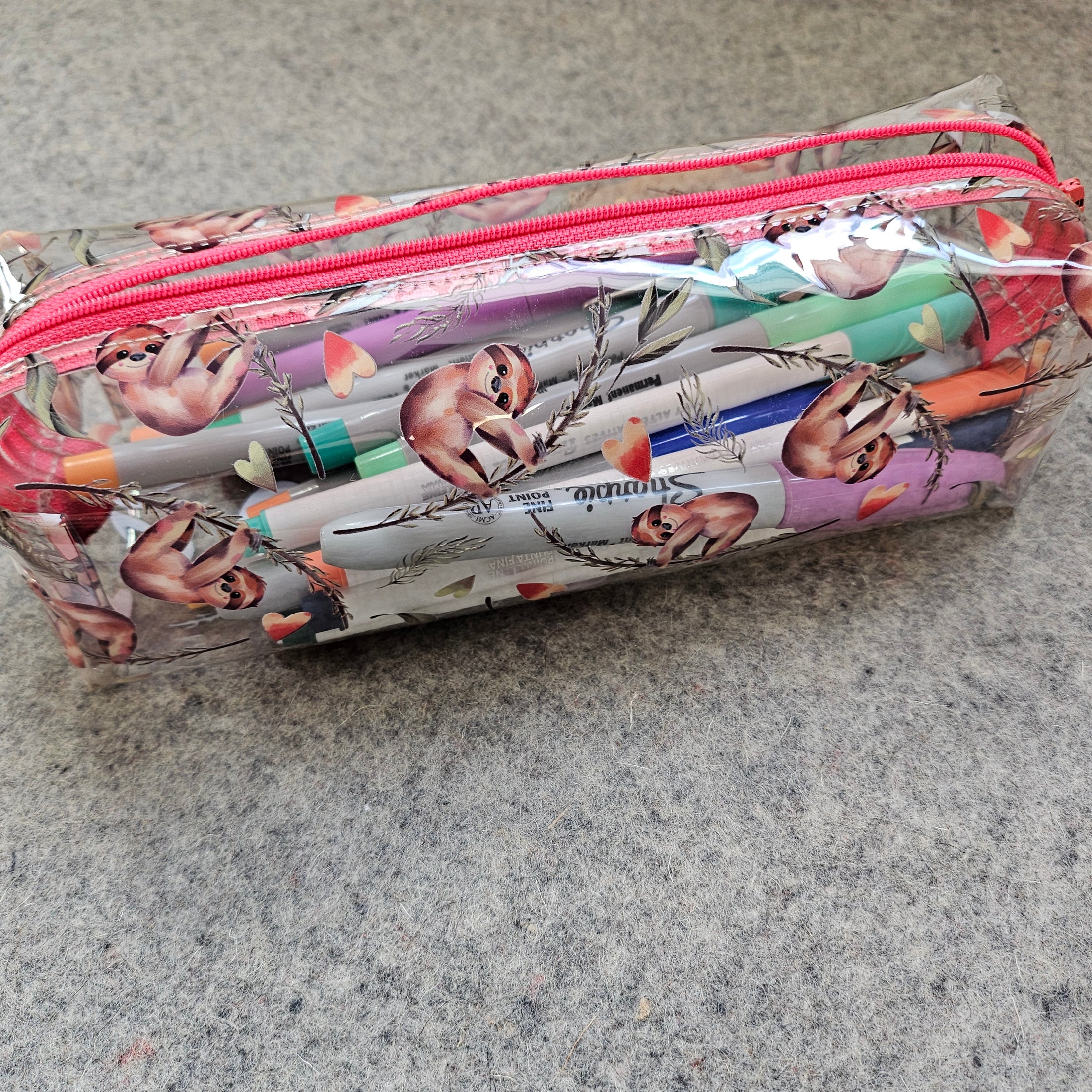 Pencil case with sloth design on a gray surface