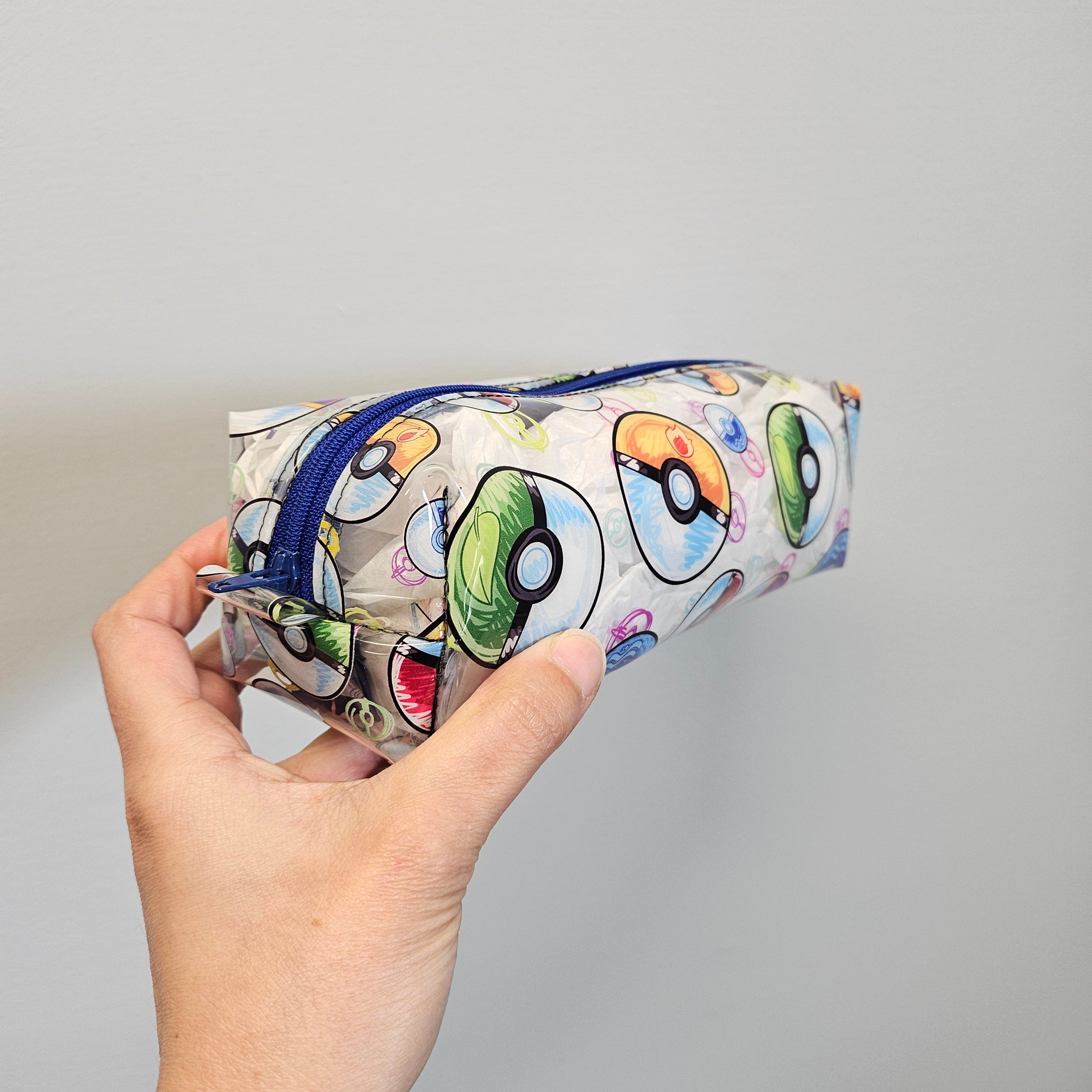 Pouch with colorful designs held by a hand against a gray background