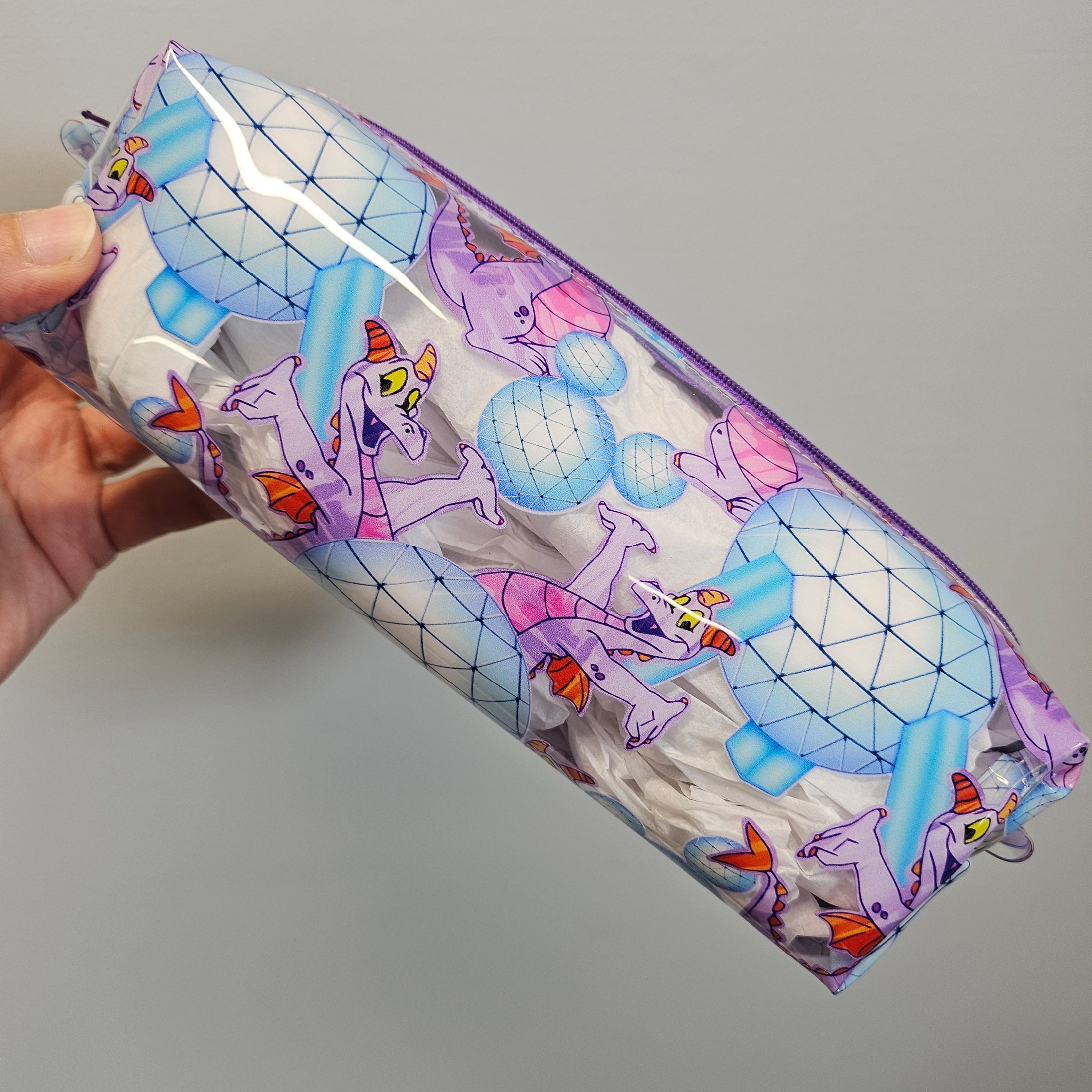 Pouch with cartoon character design held by a hand against a gray background