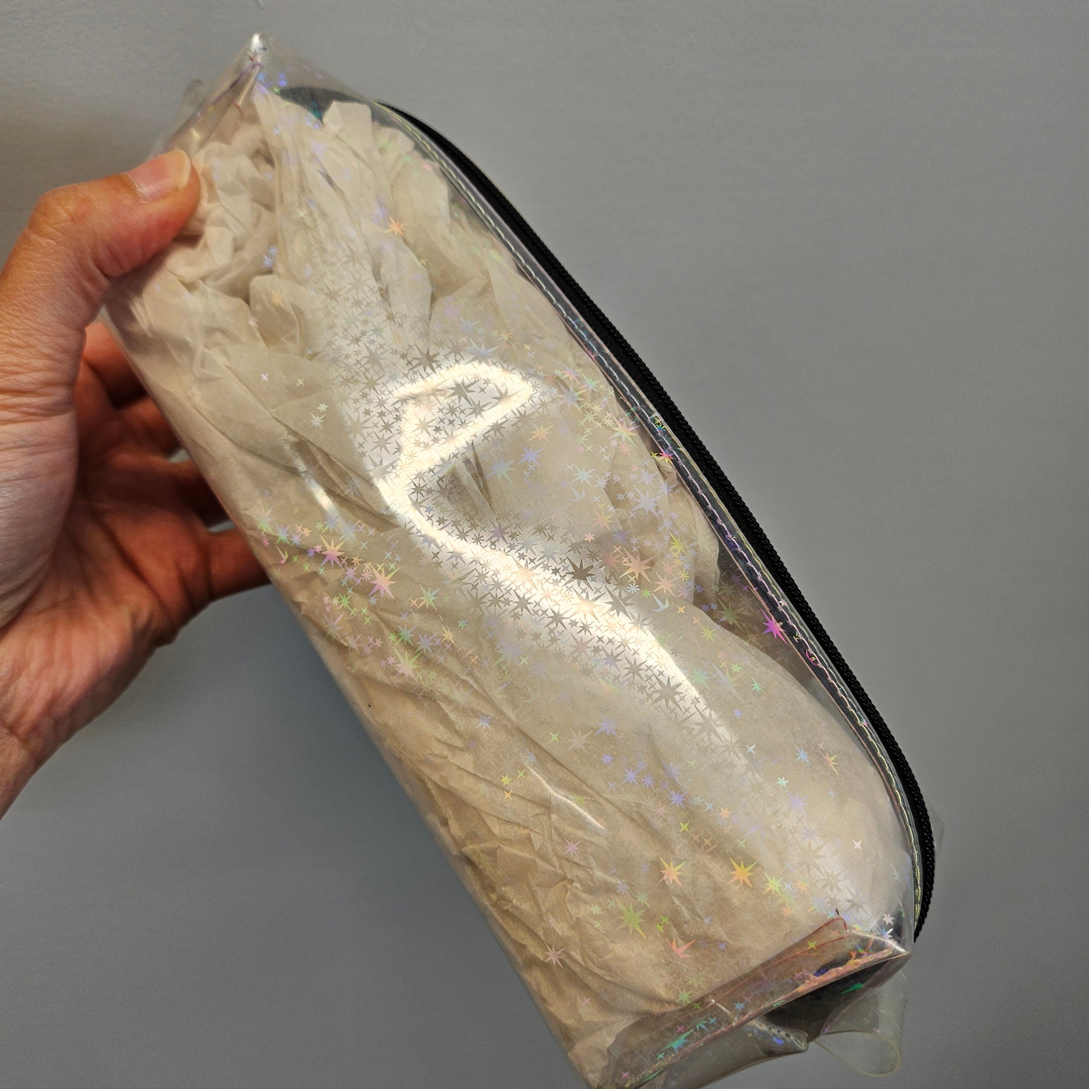 Clear plastic bag with white flowers held by a hand against a gray background
