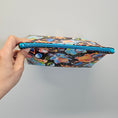 Load image into Gallery viewer, Colorful pouch with a pattern held by a hand against a gray background
