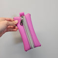 Load image into Gallery viewer, Pink pouch with a silver zipper held by a hand against a light gray background
