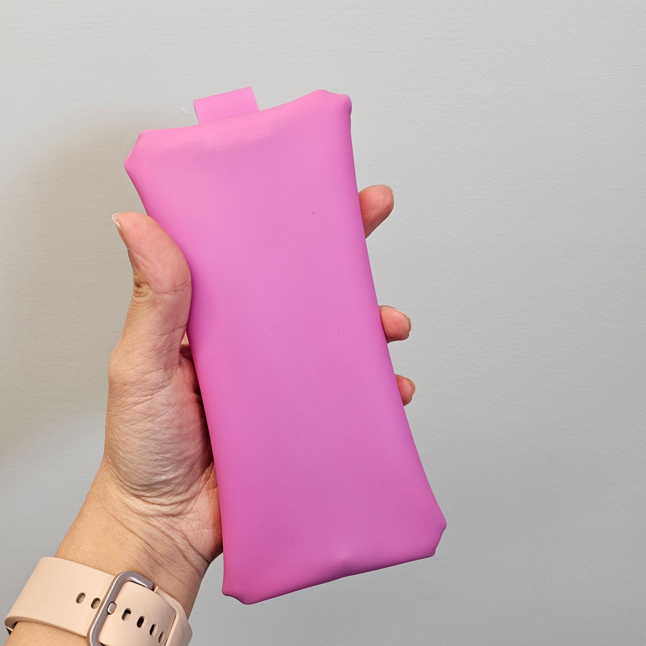 Hand holding a pink rectangular object against a plain background