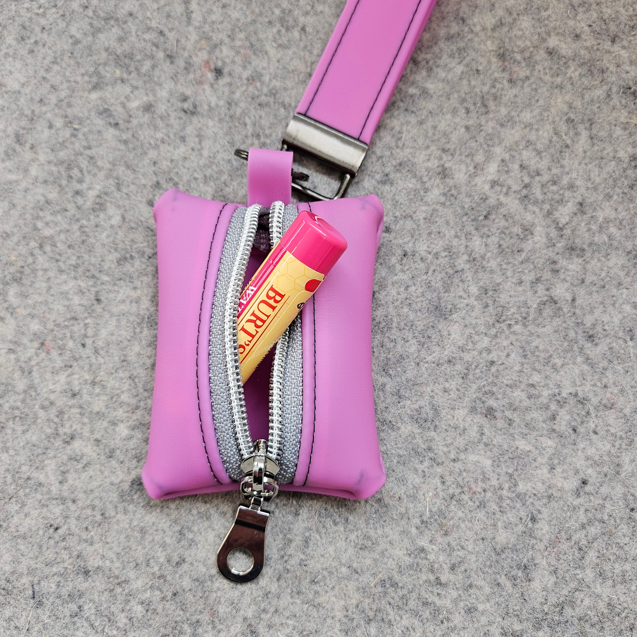 Pink pouch with a visible brand tag on a gray surface