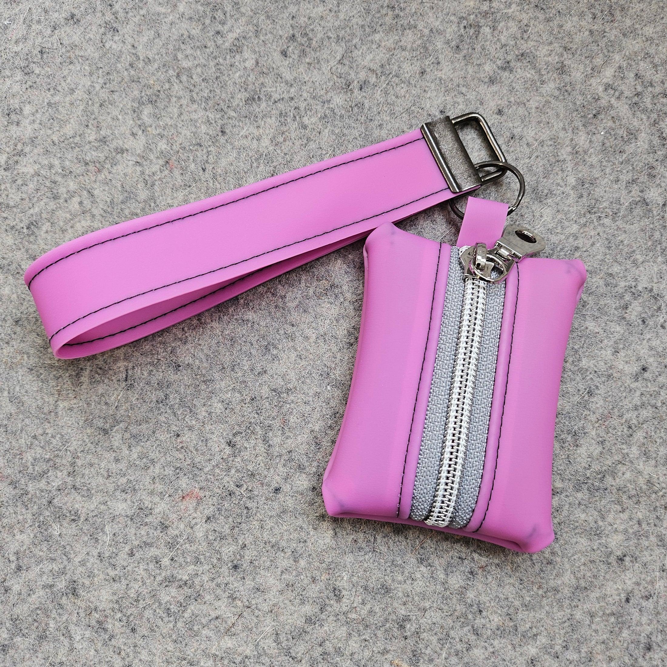 Pink keychain pouch with a strap on a gray surface
