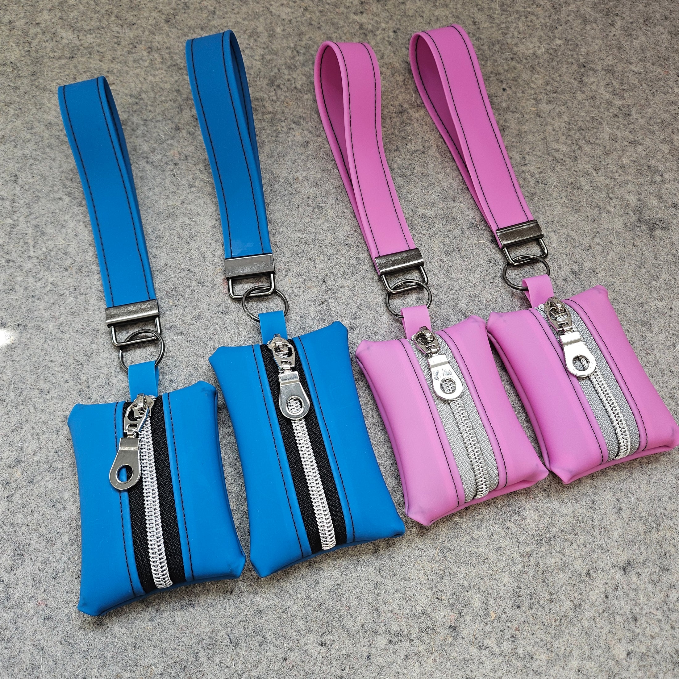 Pink and blue waist bags with zippers on a gray surface