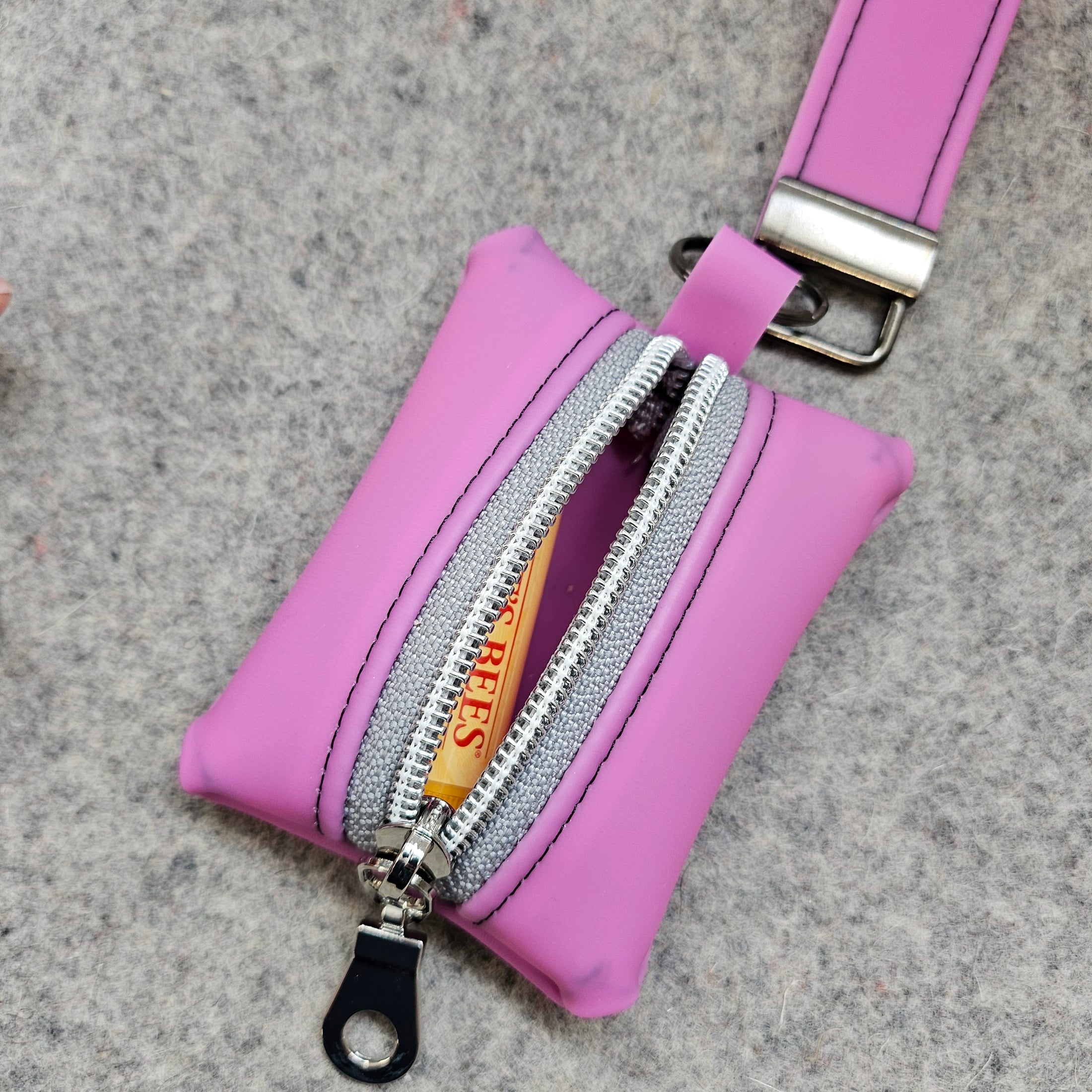 Pink keychain pouch with a visible brand logo on a gray surface