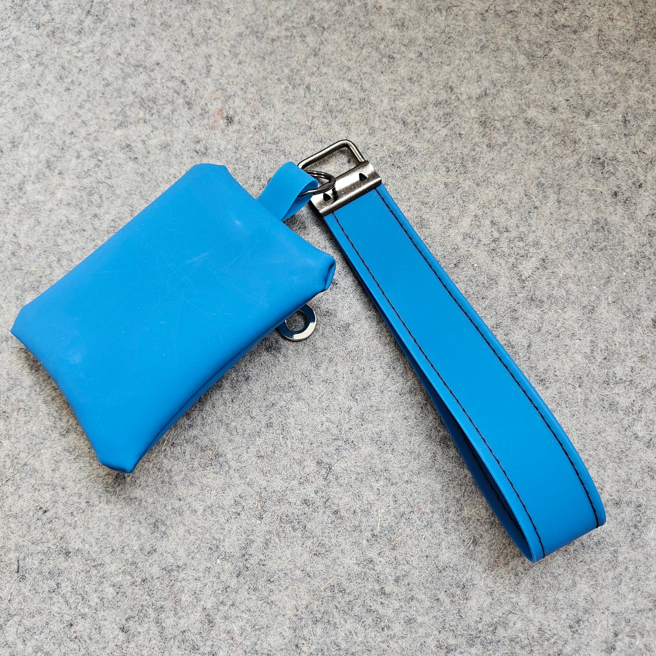 Blue leather wallet with strap on a gray surface
