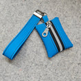 Load image into Gallery viewer, Blue wristlet with a zipper on a gray surface
