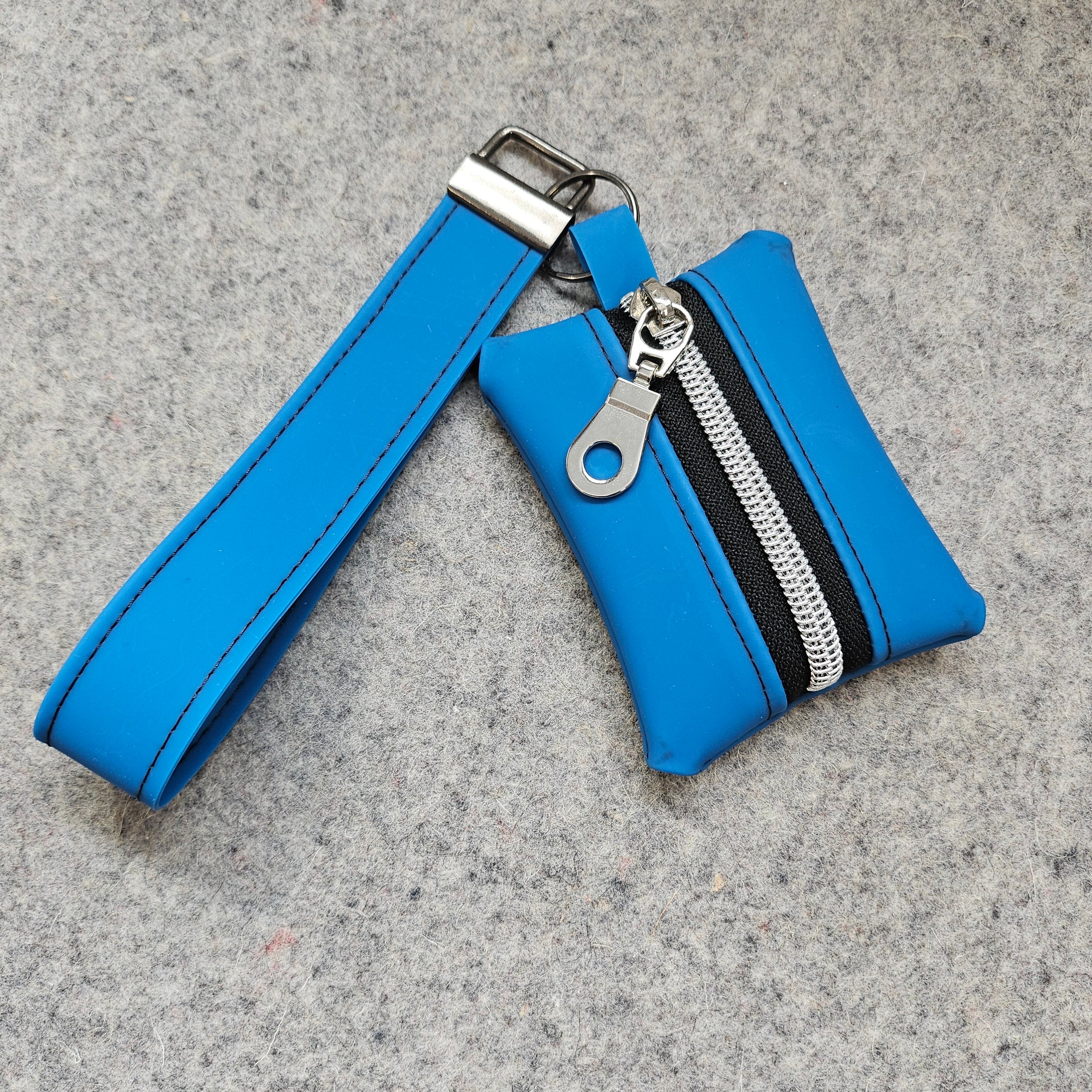 Blue wristlet with a zipper on a gray surface