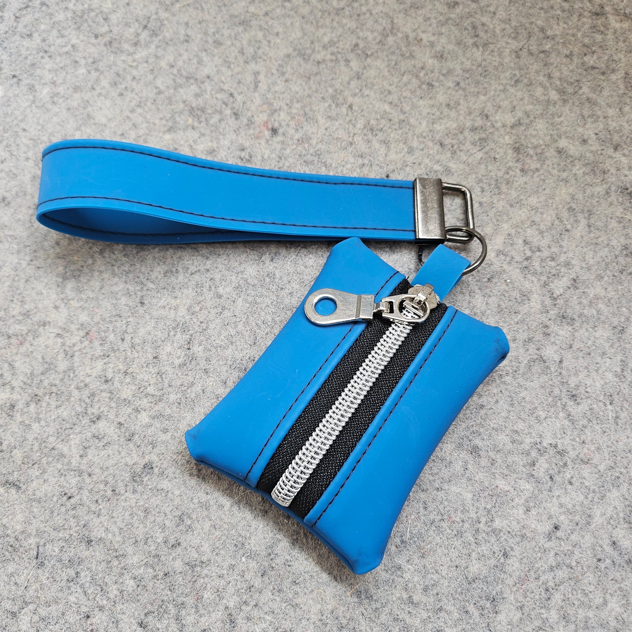 Blue wallet with a wrist strap on a gray background