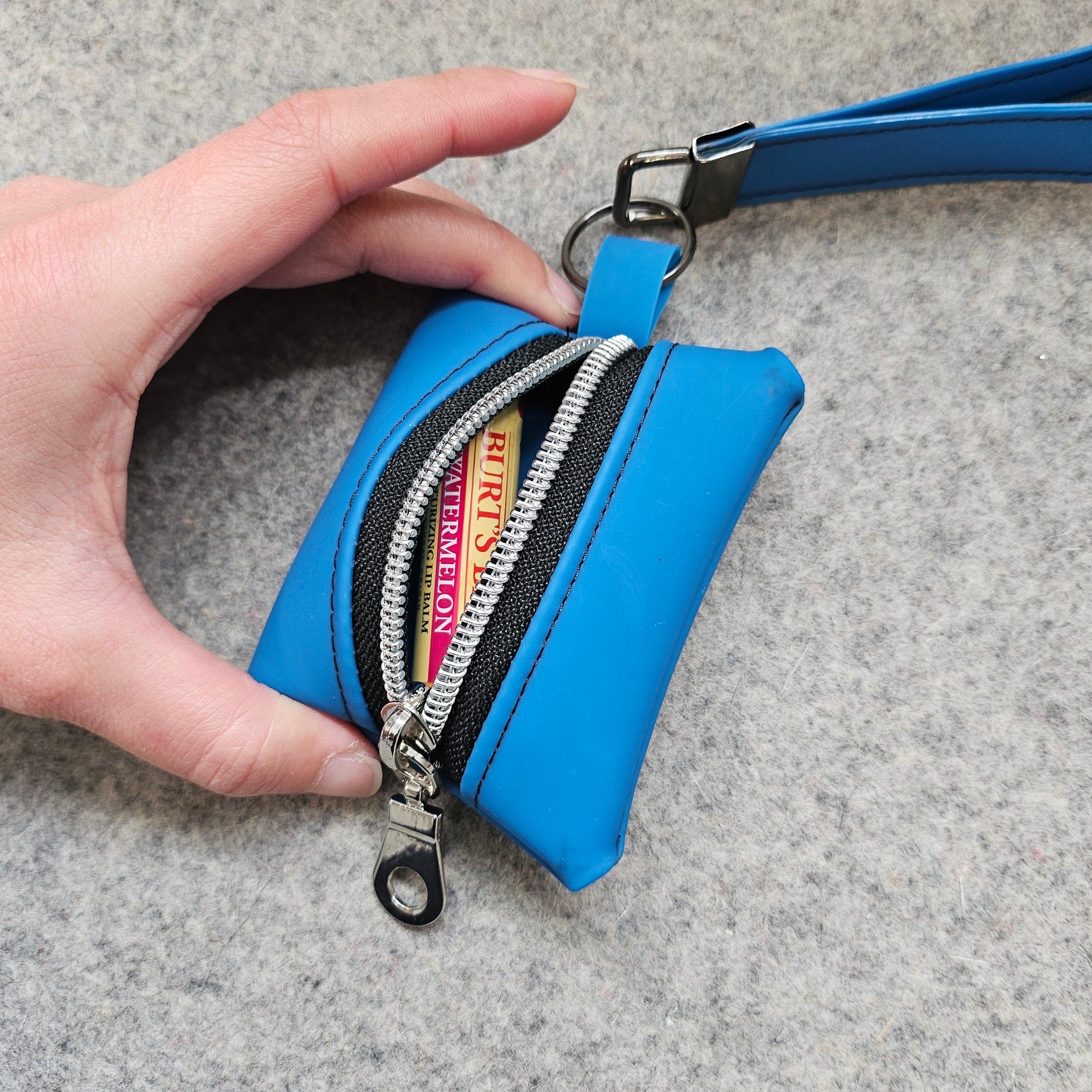 Blue wallet with a visible brand name held by a hand on a gray background