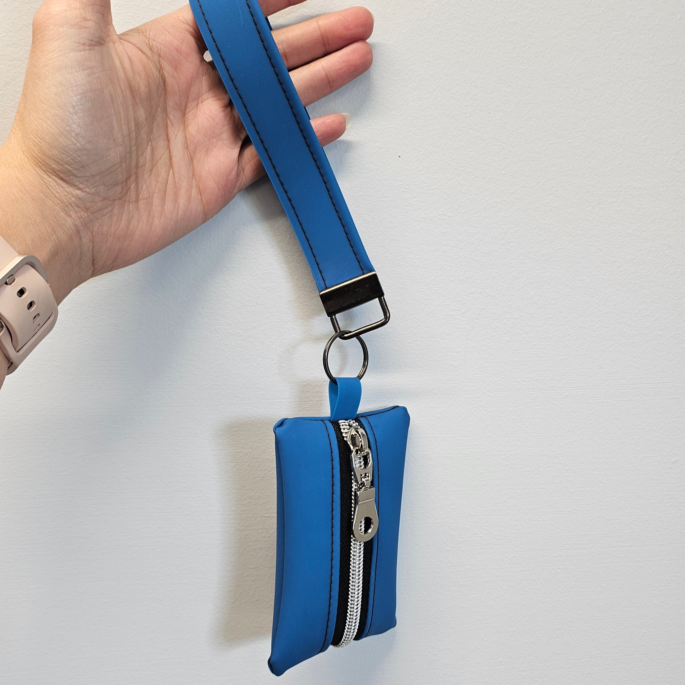 Blue strap with a keychain attachment held by a hand on a light gray background
