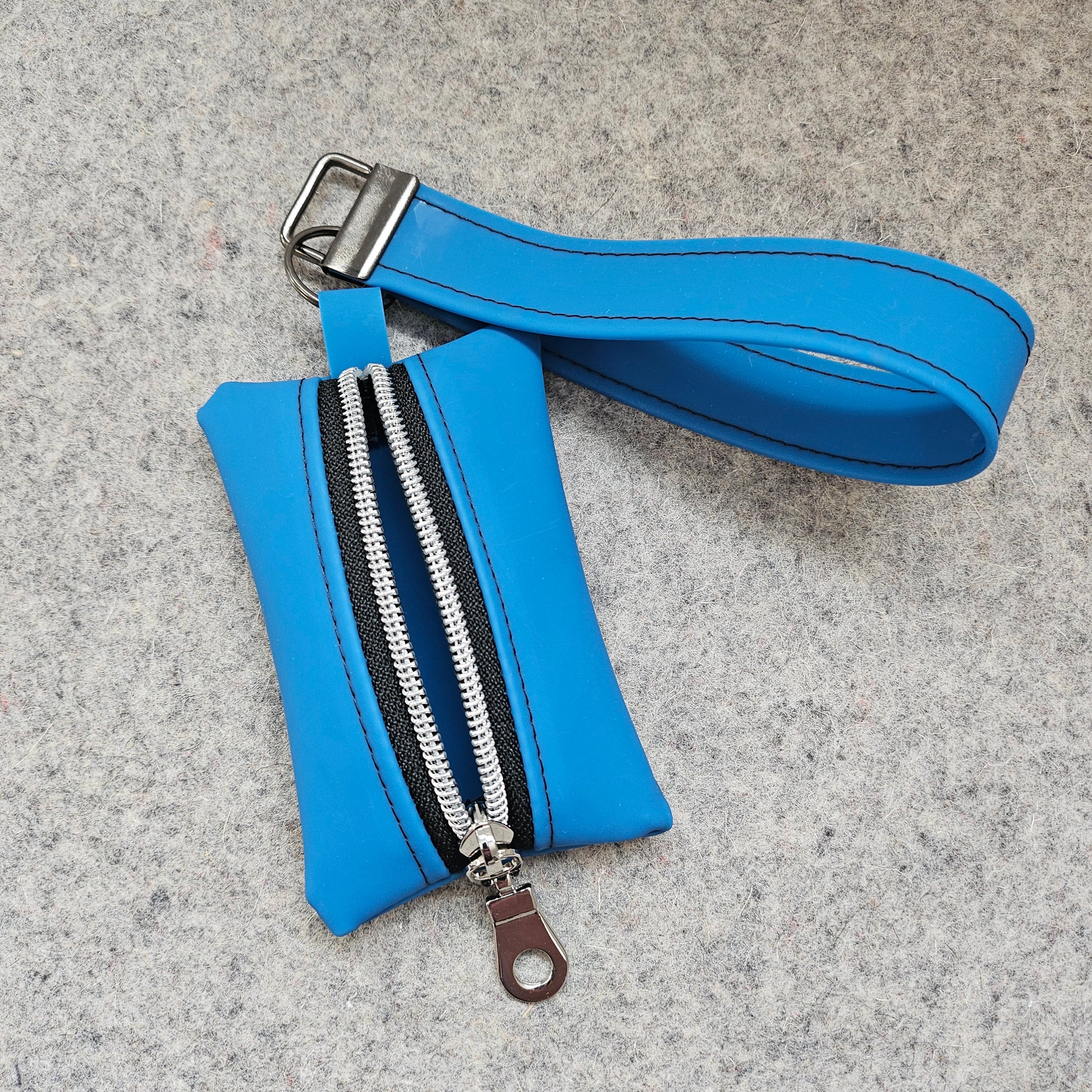 Blue pouch with a strap and zipper on a gray surface