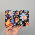 Load image into Gallery viewer, Hand holding a colorful notebook with cartoon characters on a gray background
