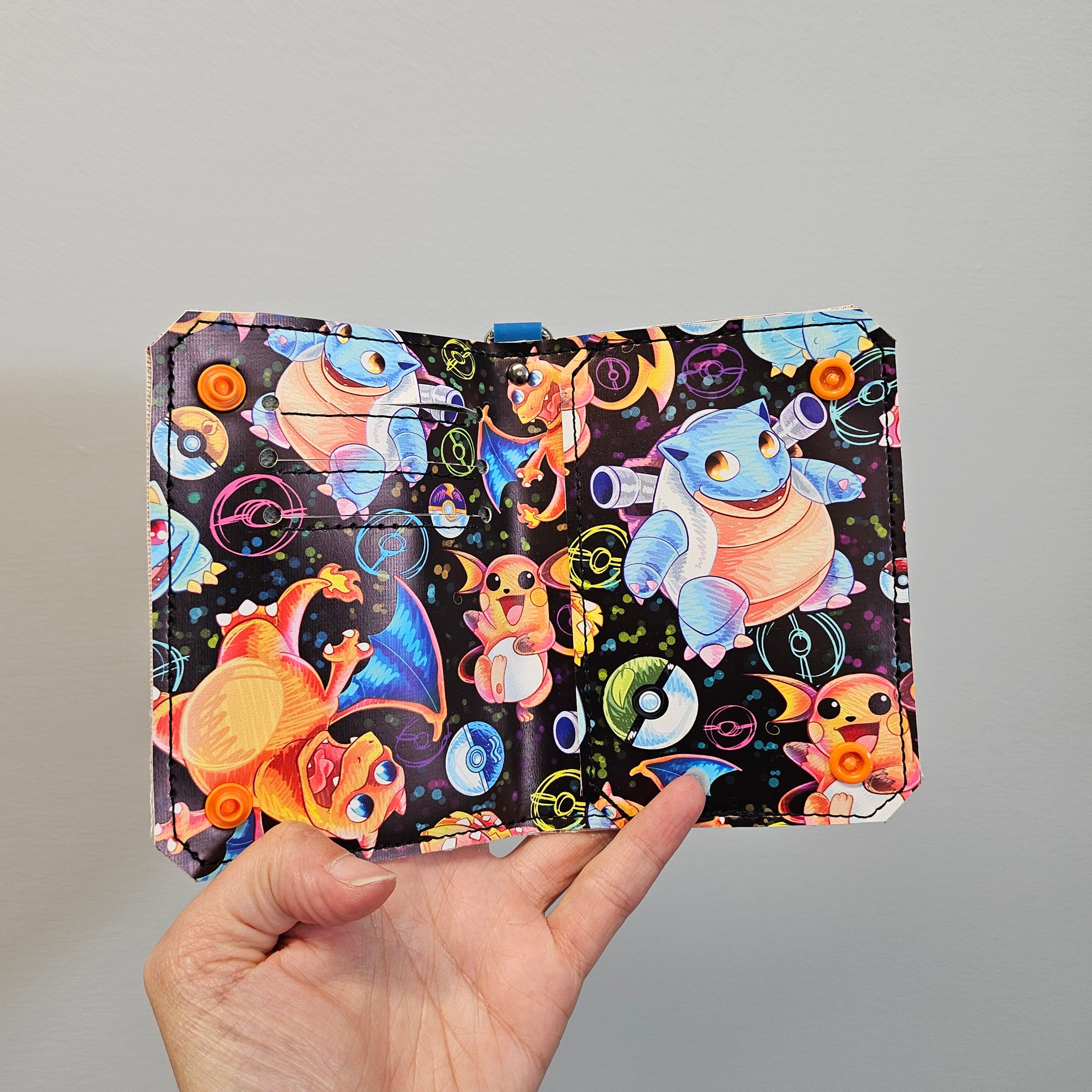 Hand holding a colorful notebook with cartoon characters on a gray background