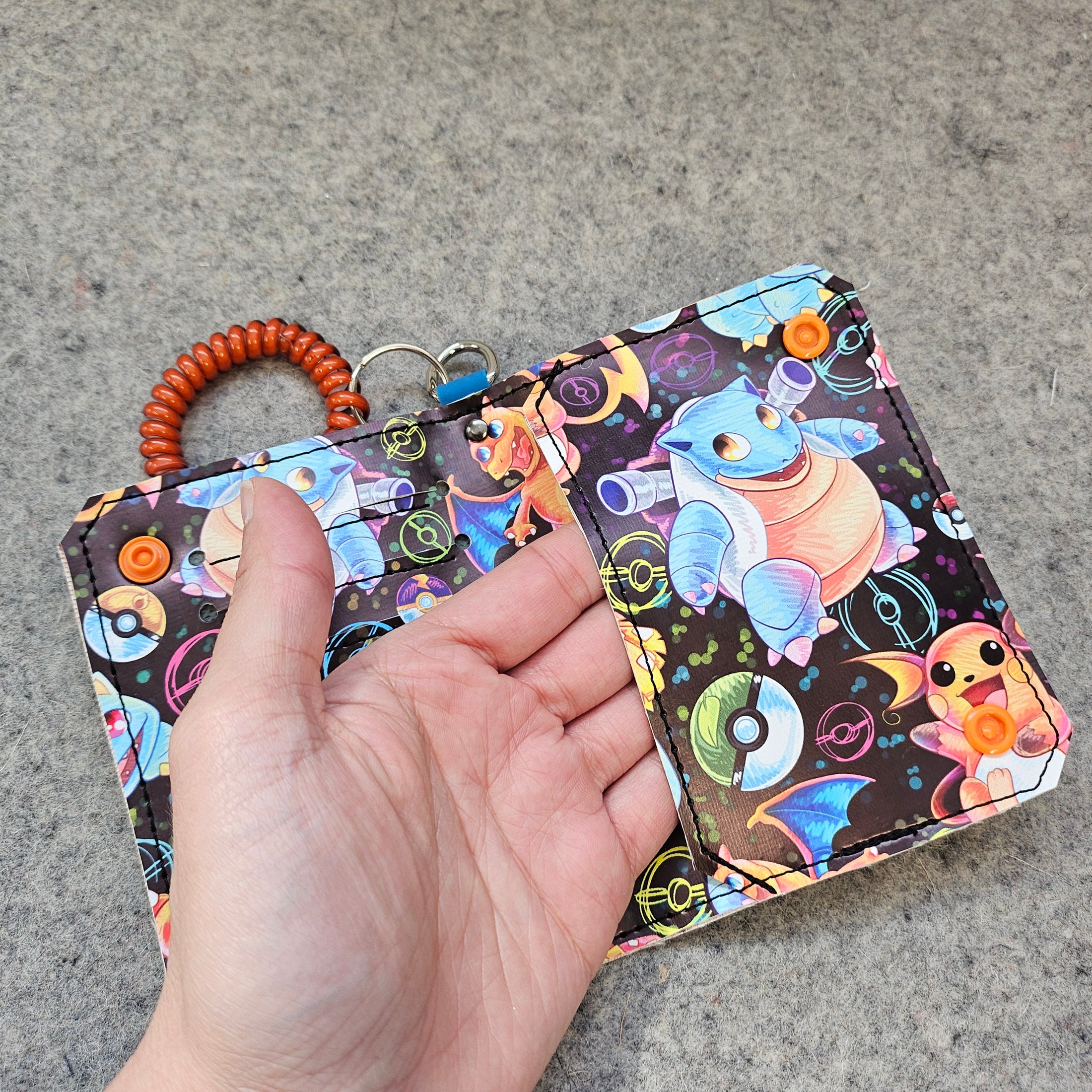 Colorful keychain with cartoon character held by a hand on a concrete surface