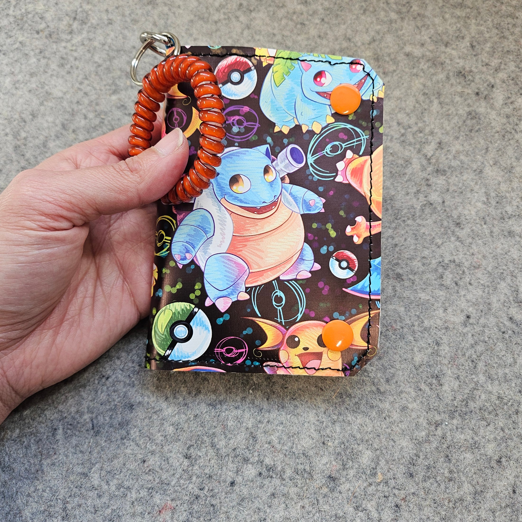 Colorful wallet with cartoon character held by a hand on a gray surface