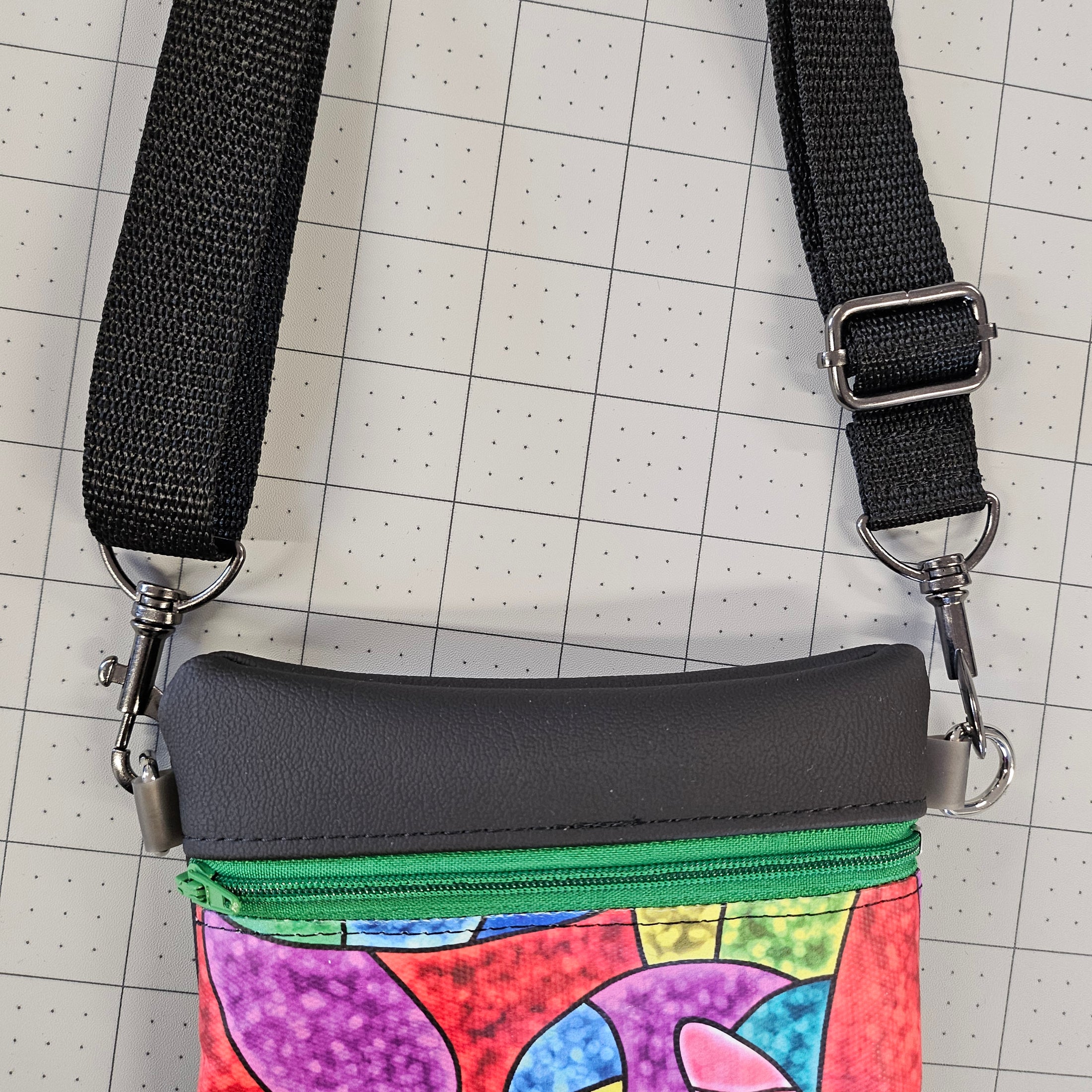 Colorful pouch with a black strap on a grid background