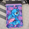 Load image into Gallery viewer, Blue cartoon character on a purple and pink patterned bag on a grid background
