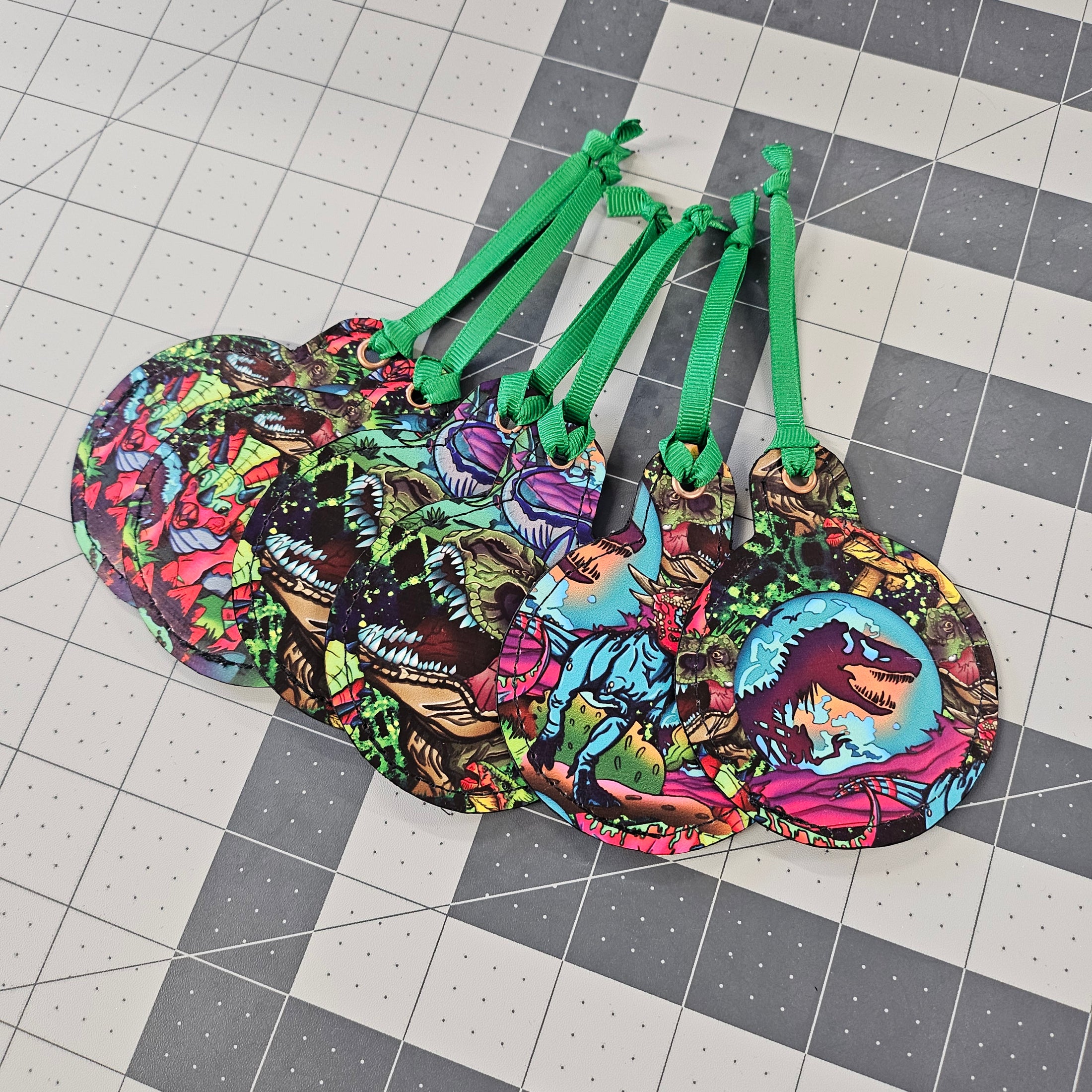 Dinosaur ornaments with green ribbon on a grid like surface.