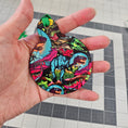 Load image into Gallery viewer, Hand holding a velociraptor ornament.
