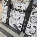 Load image into Gallery viewer, Bag with zodiac pattern and black straps on a checkered floor
