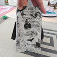 Load image into Gallery viewer, Hand holding a small rectangular pouch with black and white pattern on a grid background
