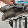 Load image into Gallery viewer, Handbag with patterned lining held open on a checkered surface
