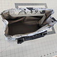 Load image into Gallery viewer, Close-up of a jacket with patterned lining on a grid background
