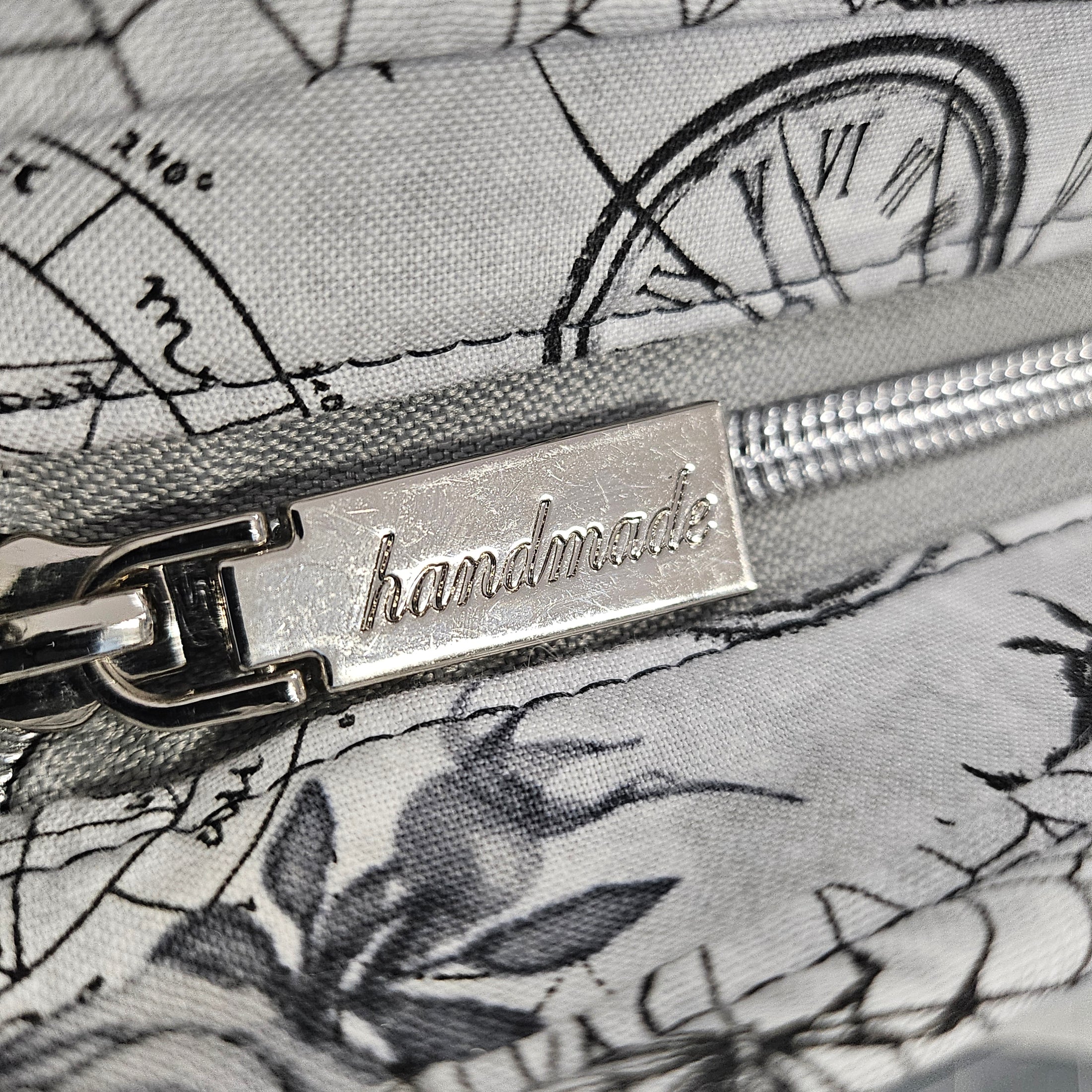 Close-up of a zipper with 'handmade' label on floral fabric background