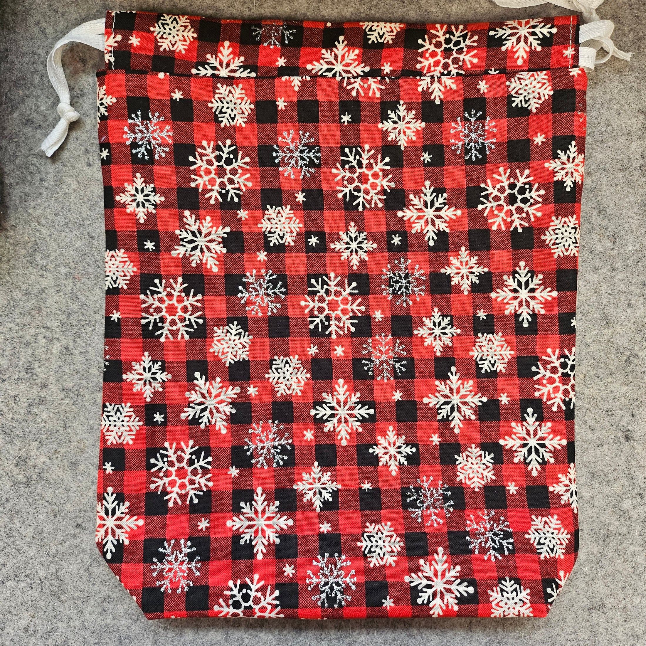 Red and black plaid gift bag with white snowflakes.