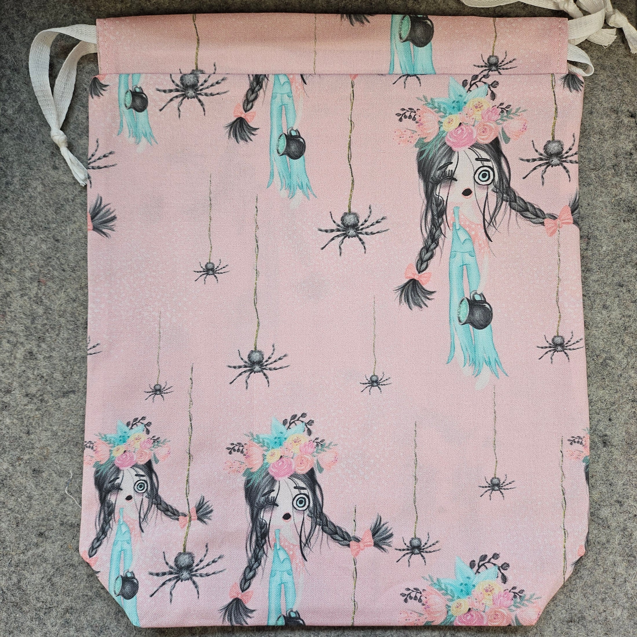 Pink bag with black spider design on a gray surface