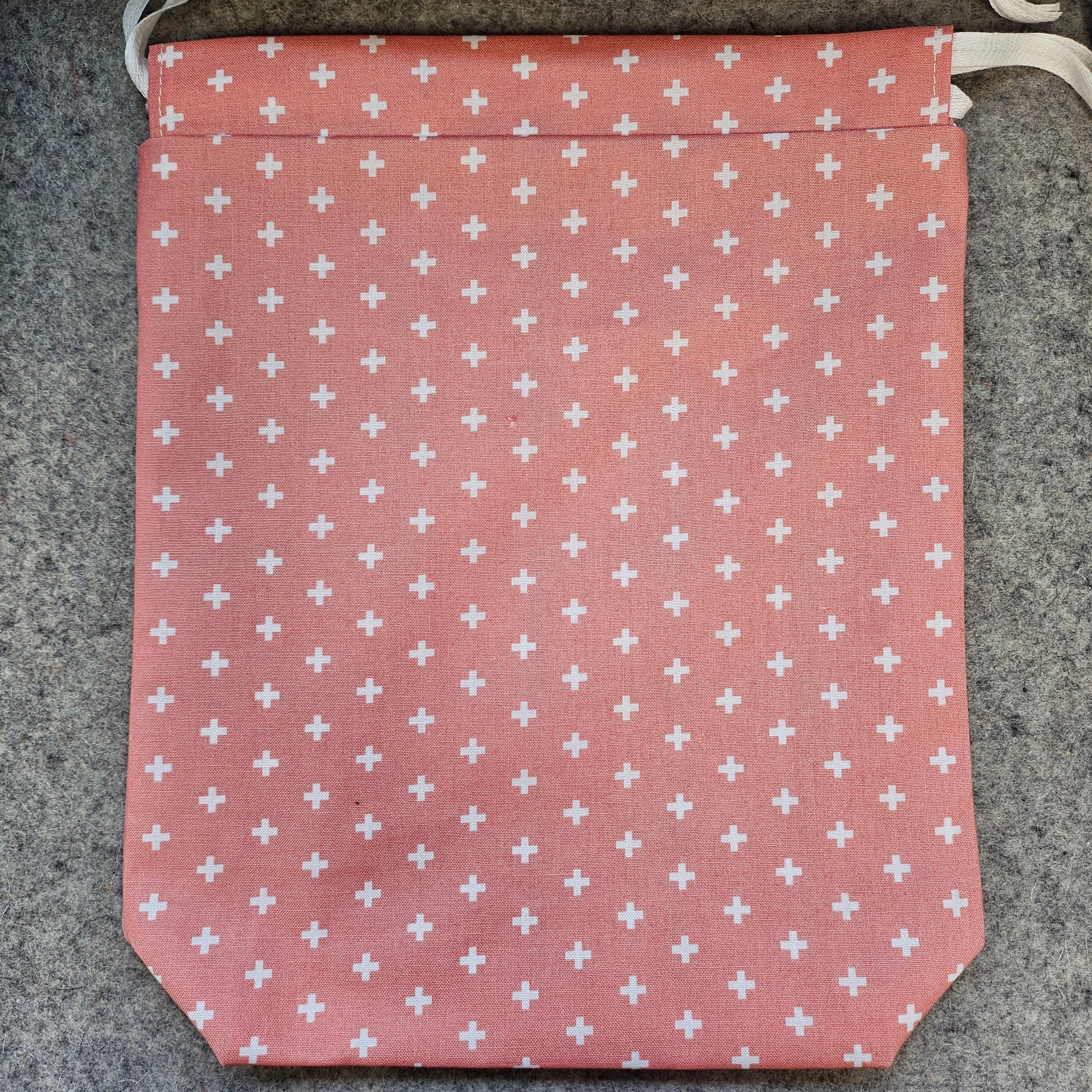 Peach colored drawstring bag with white x's.