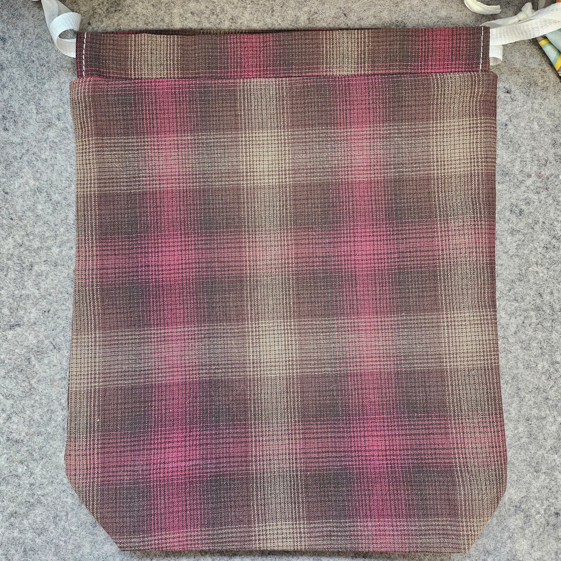 Brown and pink plaid drawstring bag.